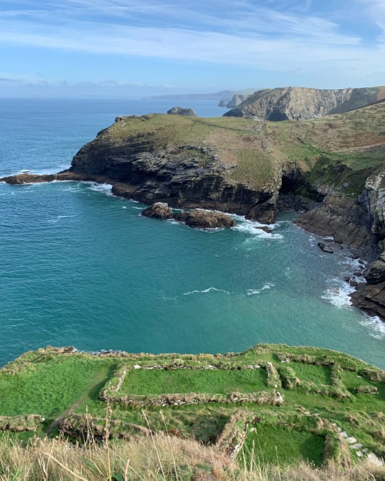 A winding sandy path under a green bush that has grown into an archway The coast path near Polperro
